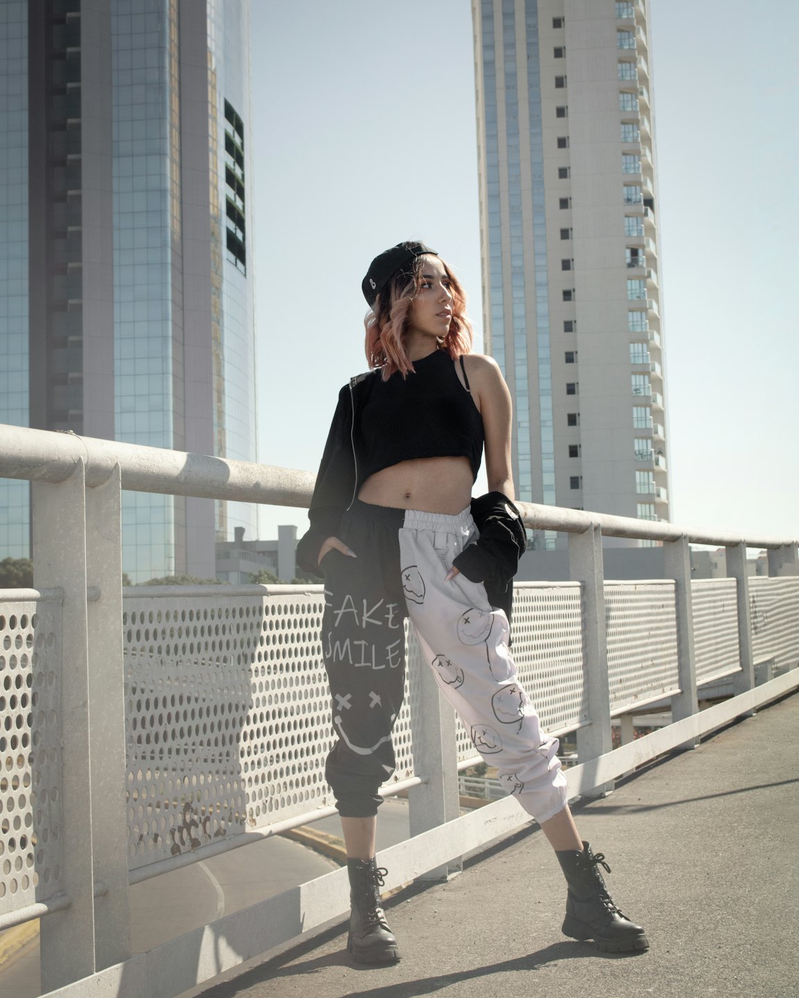 Person with pink hair models streetwear on an urban walkway.