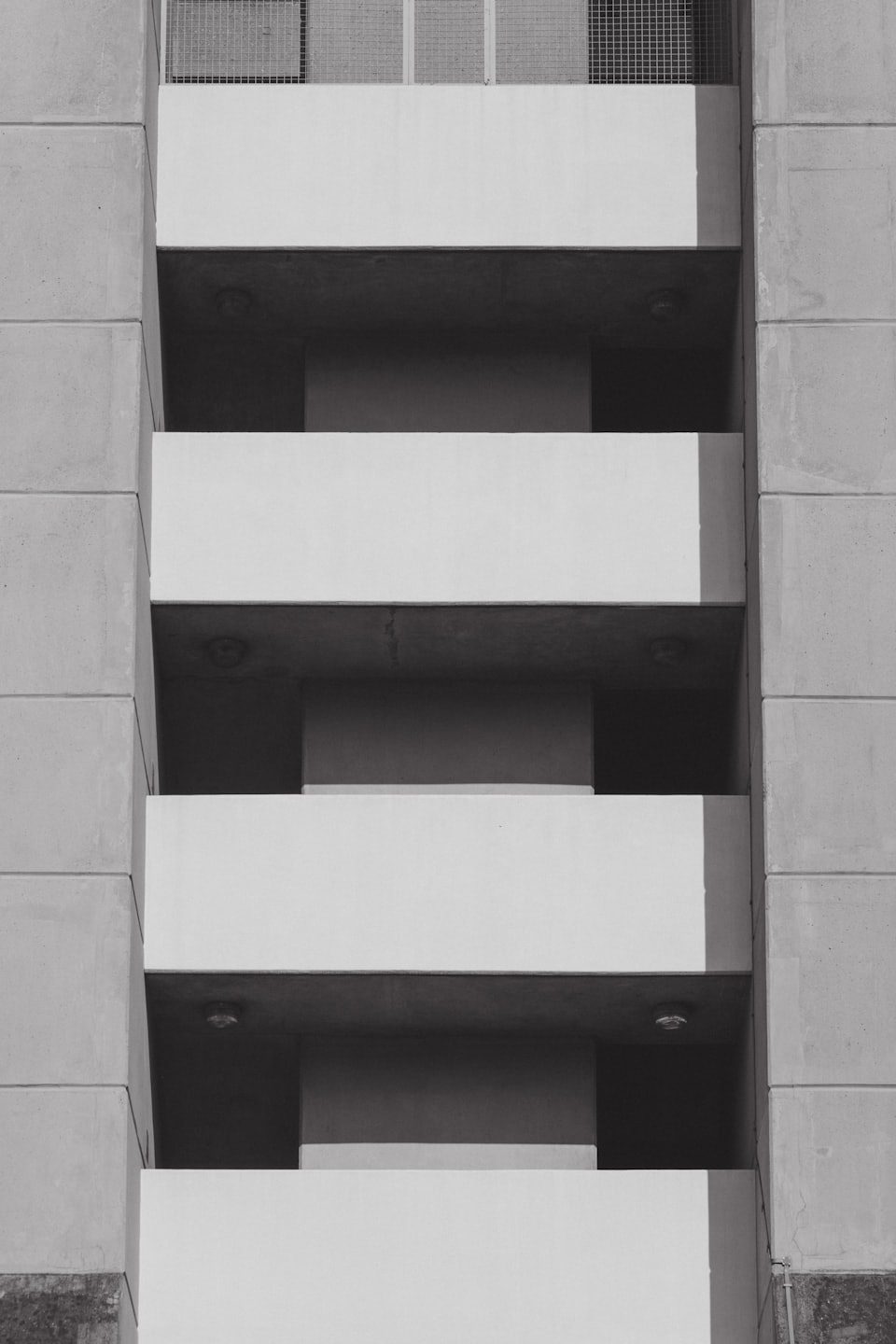 Light grey concrete ledges and dark recessed spaces on a building.