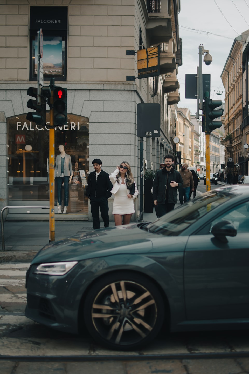 Three stylish people walk across a busy city street.