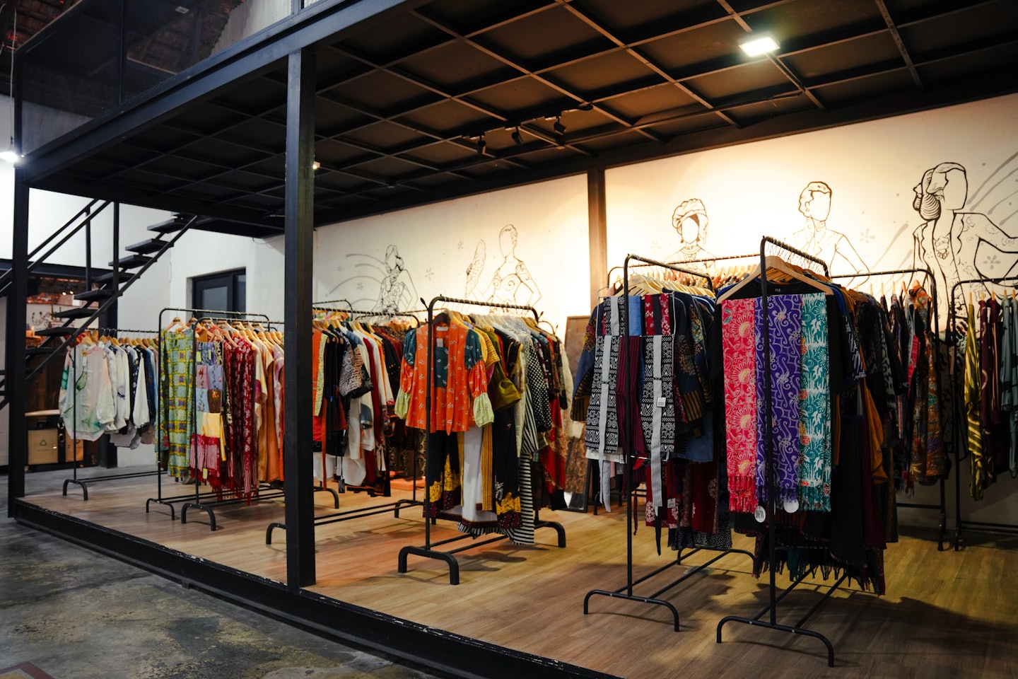 Clothing boutique with racks of colorful patterned garments and industrial-style framing.