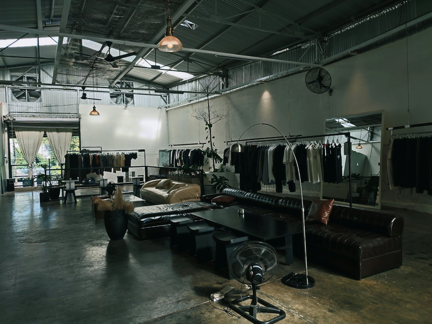 Modern boutique interior featuring clothing racks and two sofas.